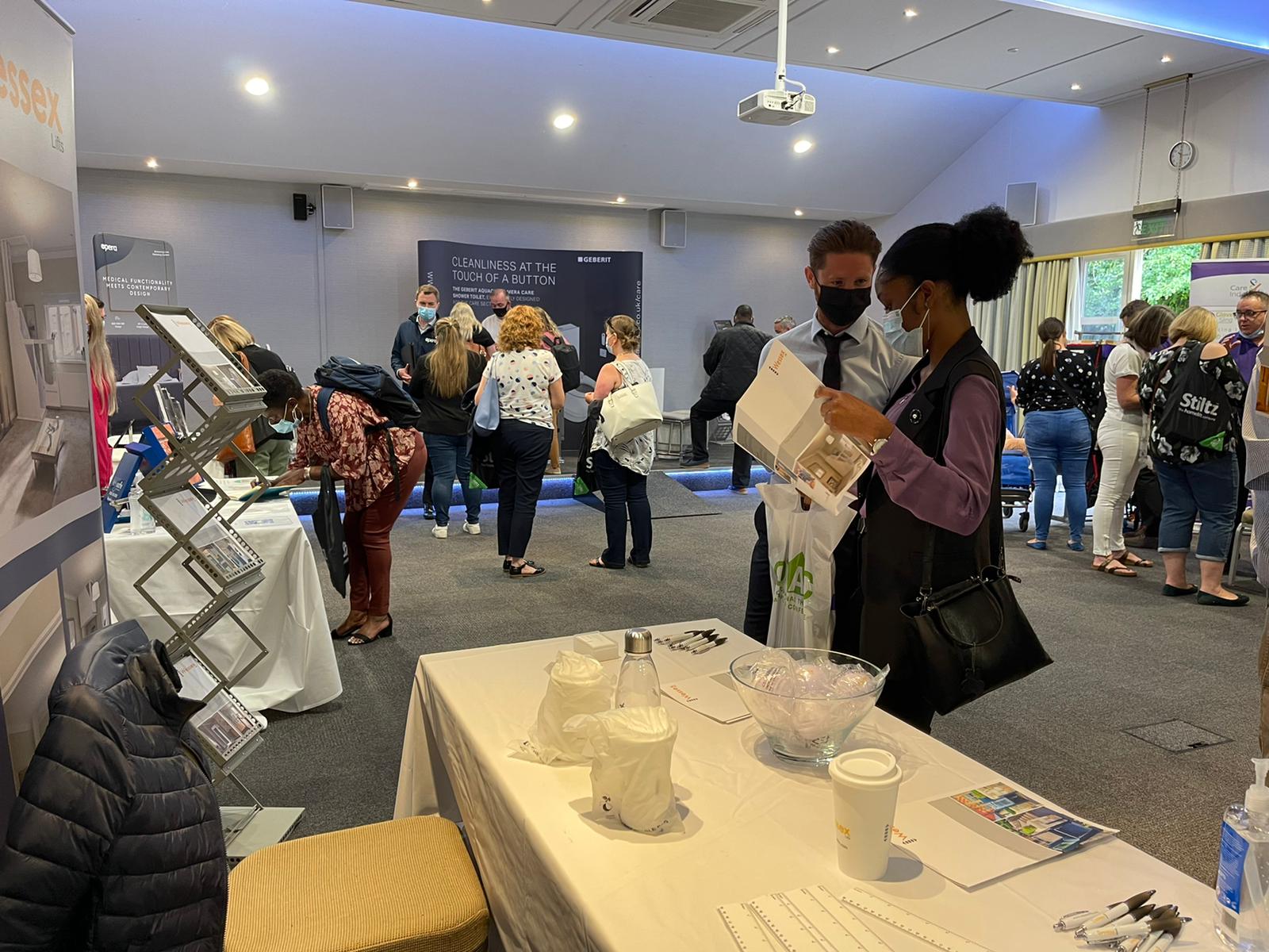 A member of our sales team discussing our products with an attendee, many of the other exhibitors can be seen in the background.